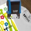 Carimbo Trodat Printy 4910 azul a marcar nome e contacto em t-shirt e papel